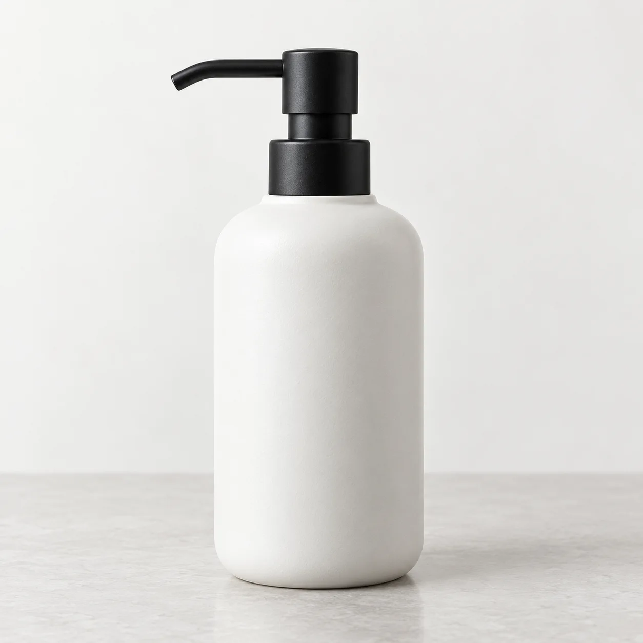 Fotografía original de un dispensador blanco mate con bomba negra sobre fondo neutro de estudio.